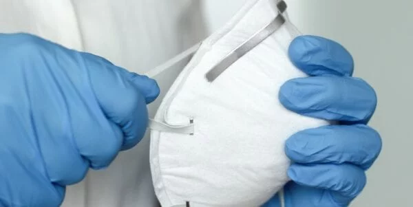 Medical mask held by gloved hands