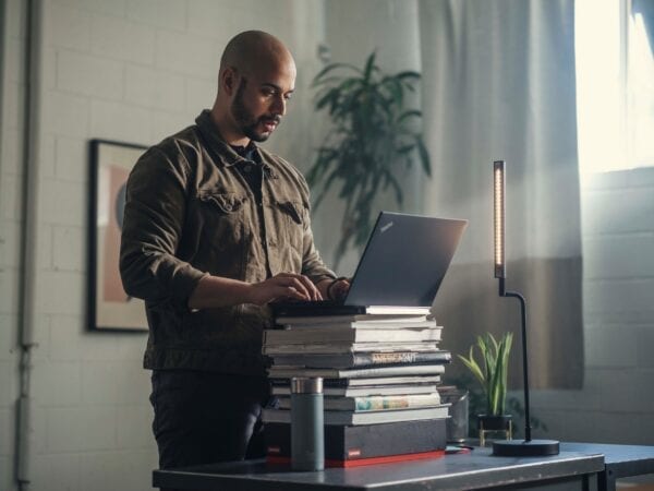 Lenovo Managed Services - person working from home with a ThinkPad on top of a stack of books.