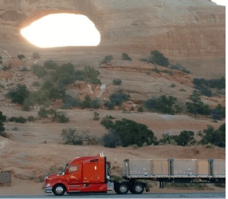 Big rig truck driving through desert scene.