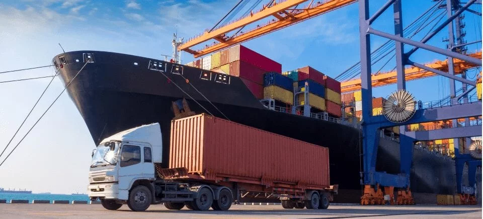 Large truck in front of cargo ship.