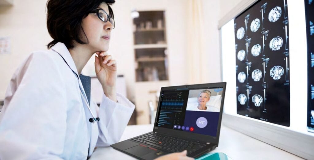 Female doctor sitting with a laptop, joining a virtual consultation and reviewing body scan images.