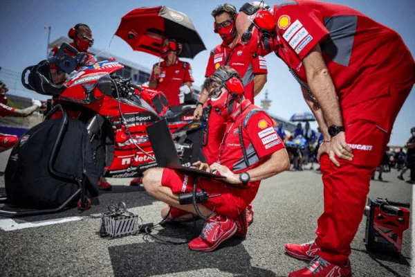 Tardozzi with a team of technicians on the MotoGP track reviewing data.