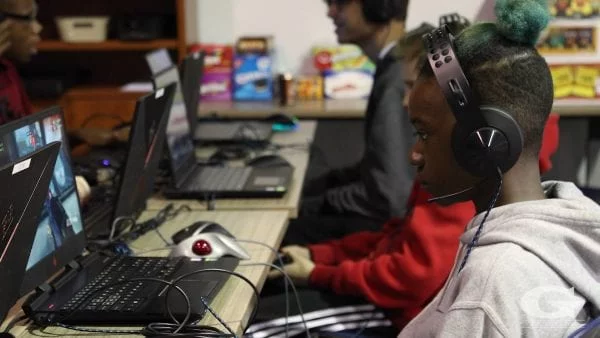 Students sitting in a row and gaming on laptops.