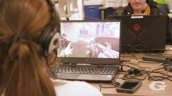 Over-the-shoulder shot of a high school student playing a game on a laptop.