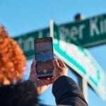 Person holding up their smartphone and aiming it at a MLK, Jr. street sign to activate the AR experience