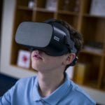 Young student using a Lenovo VR headset in the classroom.