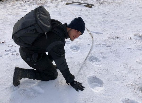 Sebastian outside in the snow examining polar bear tracks.