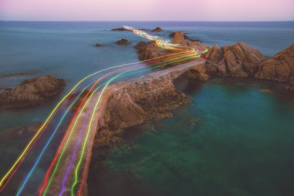Lenovo brand image showing rainbow streaks flying over rocky islands at sea.