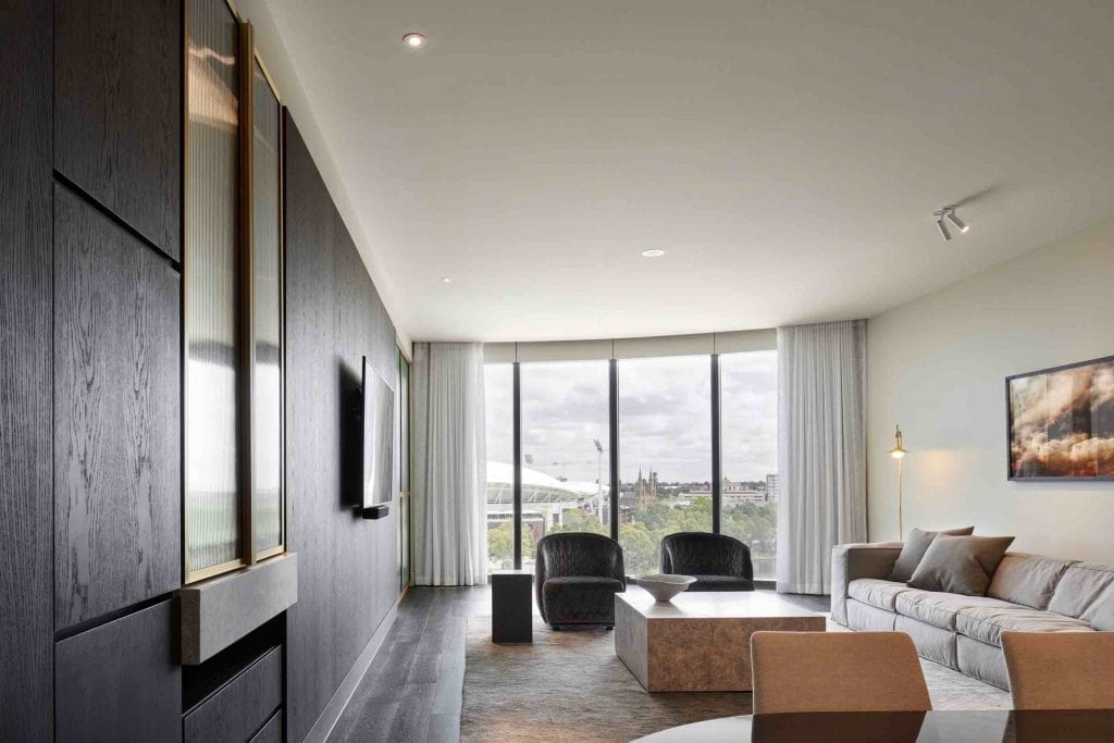 Wide view of a room inside the Adelaide Casino Hotel, featuring a large window, couch, chairs, and table.