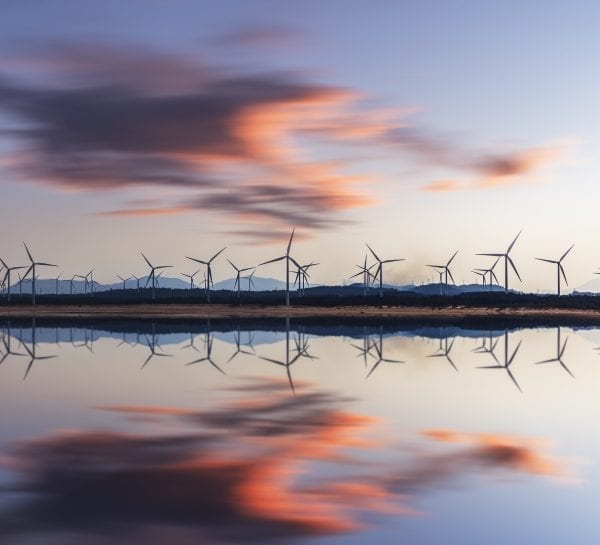 Lenovo brand image - wind turbines in the distance on the edge of water, with clouds and turbines reflected in the water's surface