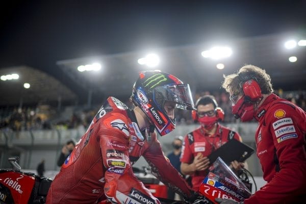 Ducati racer seated on the motorbike in the foreground with team members in the back