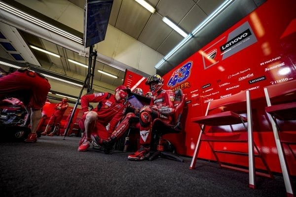 Ducati driver sitting and reviewing data on a laptop while consulting with another team member