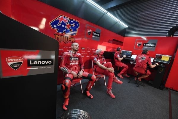 Ducati team dressed in bright red, some waiting while others review data