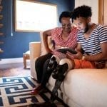 Lenovo brand image - older woman and younger man (with prosthetic legs) looking at a handheld device together