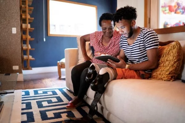 Lenovo brand image - older woman and younger man (with prosthetic legs) looking at a handheld device together