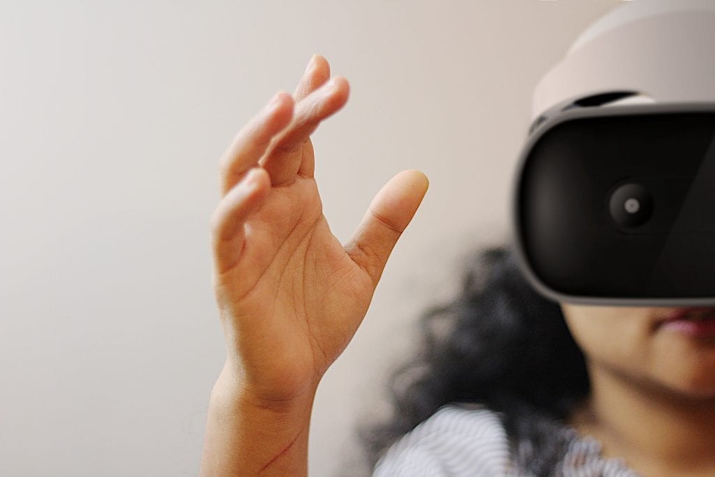 Young child reaching forward while wearing a VR headset. Image focuses on the hand, with the child's face blurred in the background