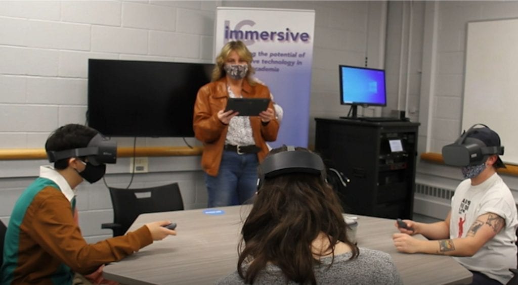 Three students at Ithaca College use Lenovo VR Classroom solutions to learn as they sit around a table wearing VR headsets.