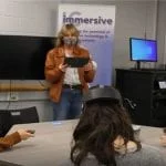 Three students at Ithaca College use Lenovo VR Classroom solutions to learn as they sit around a table wearing VR headsets.
