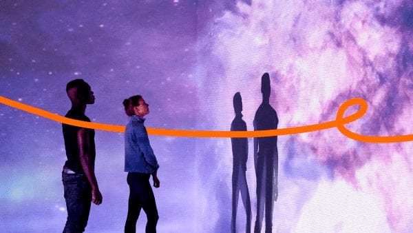 Lenovo Beyond Boundaries image - orange ribbon moving between two people looking at a wall covered in projected nebulae