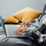 Person sitting on a couch using a Lenovo Yoga laptop