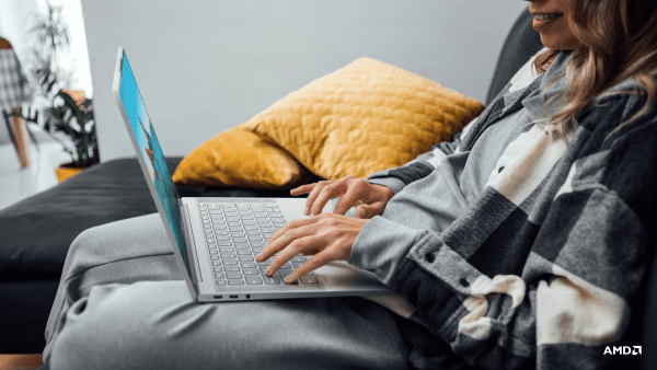 Person sitting on a couch using a Lenovo Yoga laptop