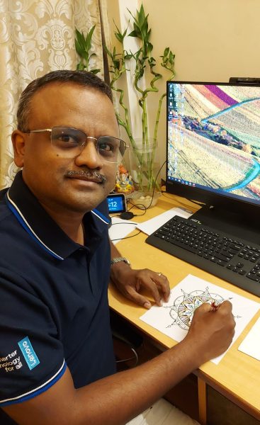 Sujai Kumar sitting at a desk creating mandala art