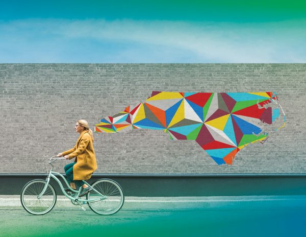 Person on bicycle riding past a wall with the state of North Carolina painted in geometric shapes