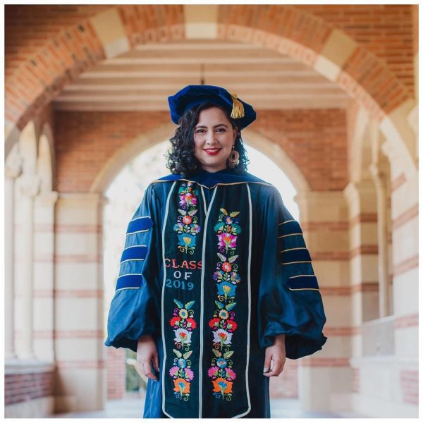 Dr. Maricela Becerra is smiling at the camera while wearing her Class of 2019 graduation gown.