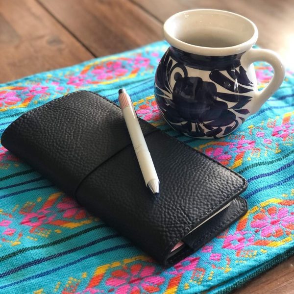 A small leather journal and a tea cup
