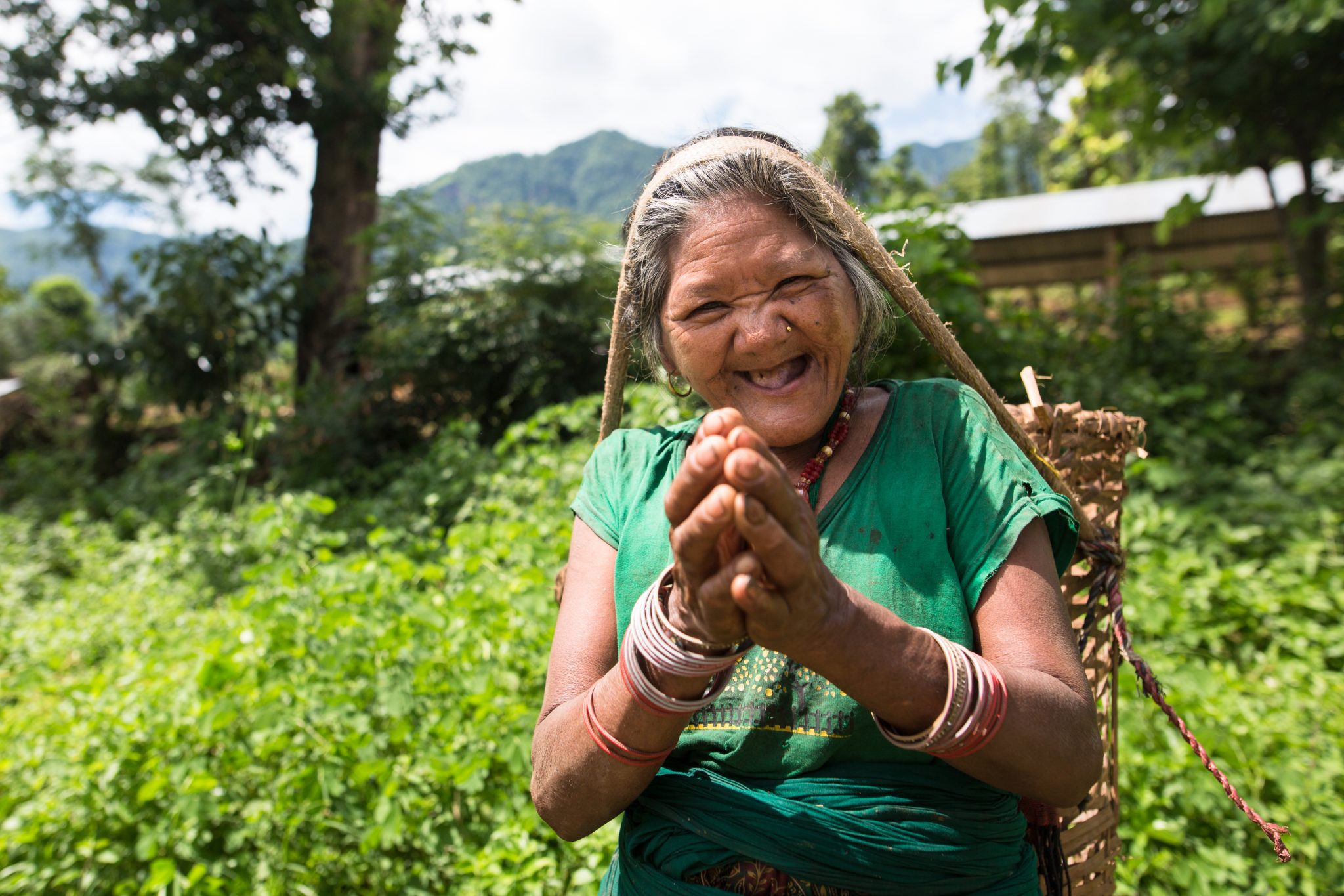 زن نپالی در ریاتوله نپال لبخند می زند و سبدی بر سر دارد