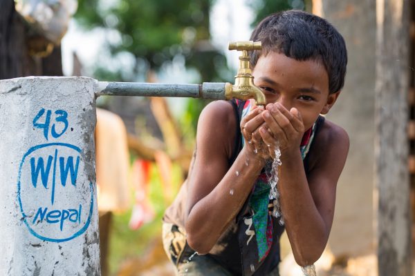 Nepali boy drinking clean water from his family's tap stand in Dahakhani, Nepal.