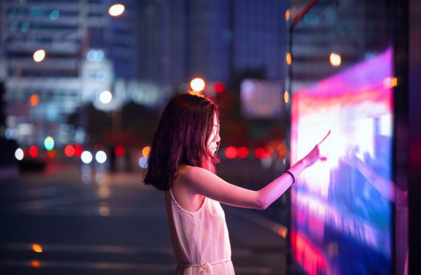 Brand image - person on city street touching digital display