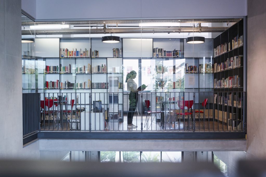 Lenovo brand image - woman in silhouette reading a book seen through interior window in a library