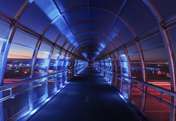 Brand image - Empty pedestrian bridge at night with red and blue lights.