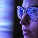 Brand image - Close-up of digital data reflected in a woman's glasses.