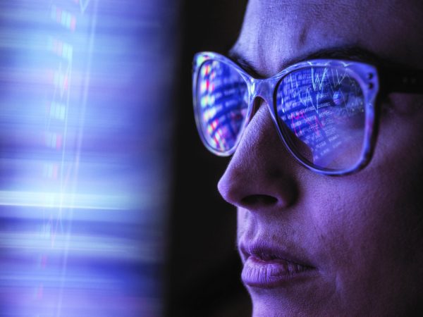 Brand image - Close-up of digital data reflected in a woman's glasses.