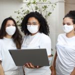 Three women with a Lenovo laptop, wearing surgical masks, Instituto Reciclar