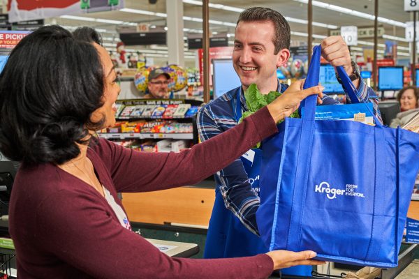 Employee at Kroger passing a full grocery bag to a customer