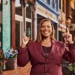 Queen Latifah outside, smiling and pointing fingers to the sky