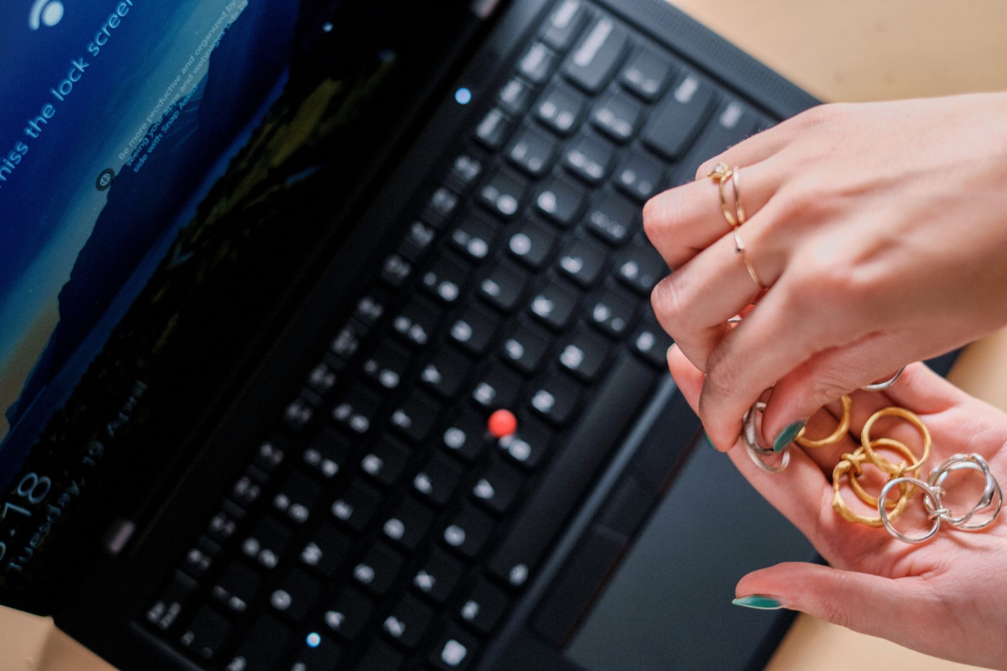 Kinetic Wabi Sabi ring made of recovered platinum from end-of-life Lenovo hardware being held over a ThinkPad X1