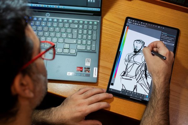 Salva Espin sitting and drawing on a Lenovo tablet and Legion laptop