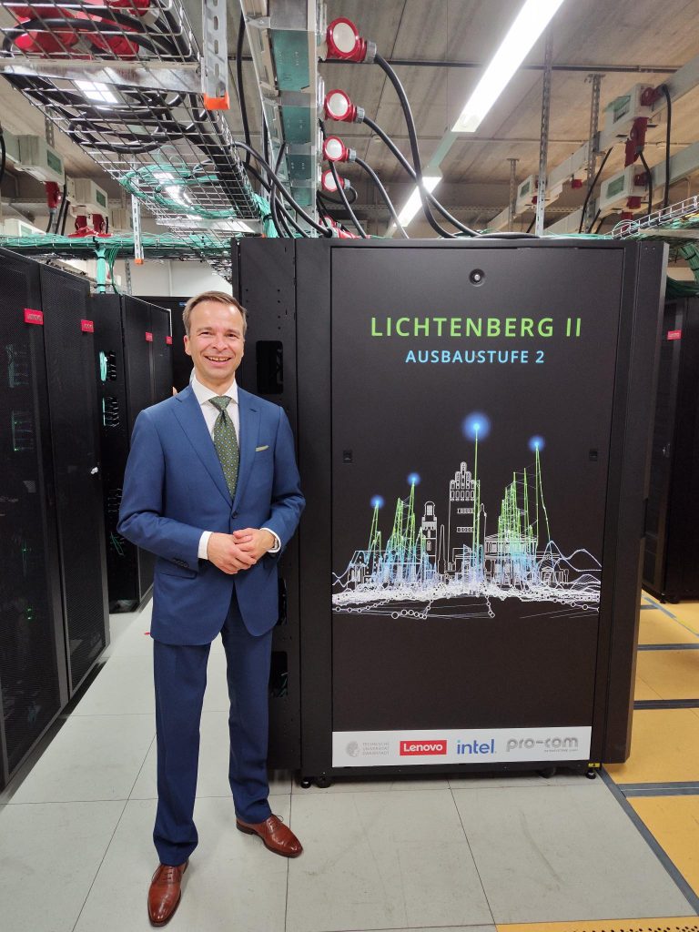 Andreas Thomasch, Director HPC & AI DACH, France, UKI standing in front of supercomputer in server room
