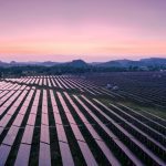 Wide view of solar panels with mountains in the background.