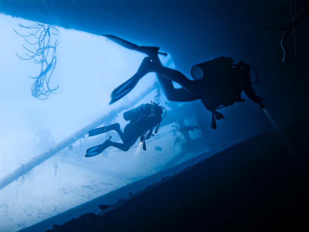 Two divers underwater Exploring the Hilma Hooker drug smuggler shipwreck