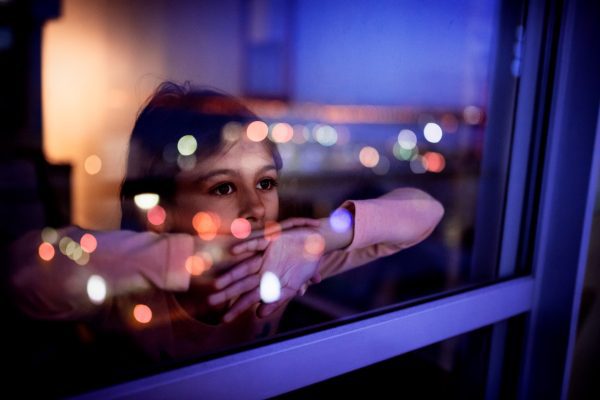 brand image - Child looking out a window at night with reflections of light