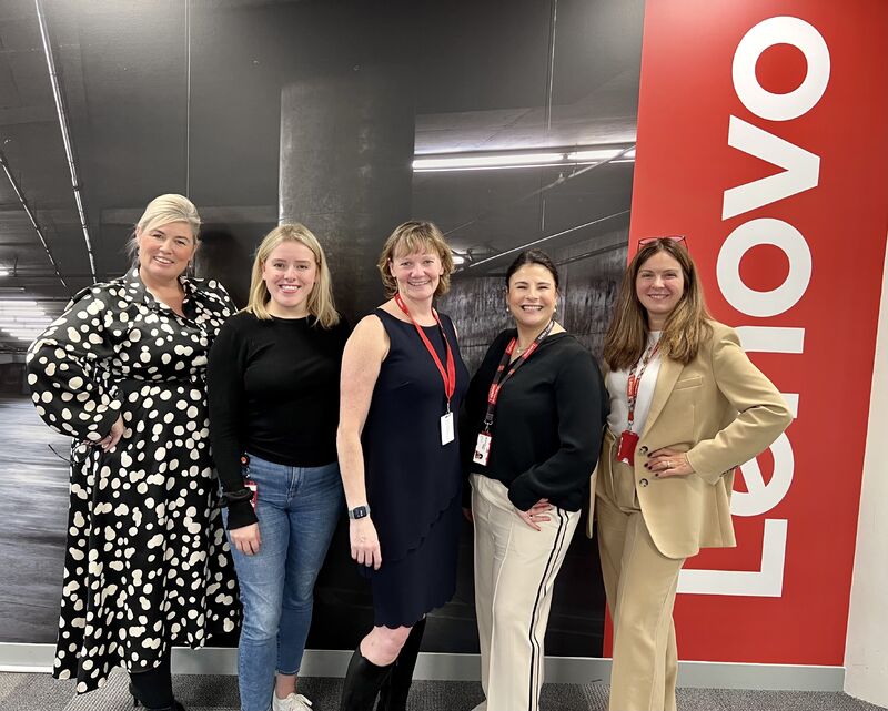 5 business women stood in front of Lenovo logo.