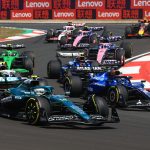 Formula 1 cars racing on a track in China with Lenovo branding behind.