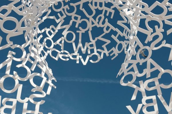 White metal letters forming a circular sculpture against a blue sky.